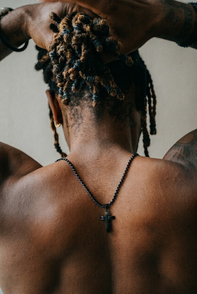 The black Apex cross necklace from the set, worn