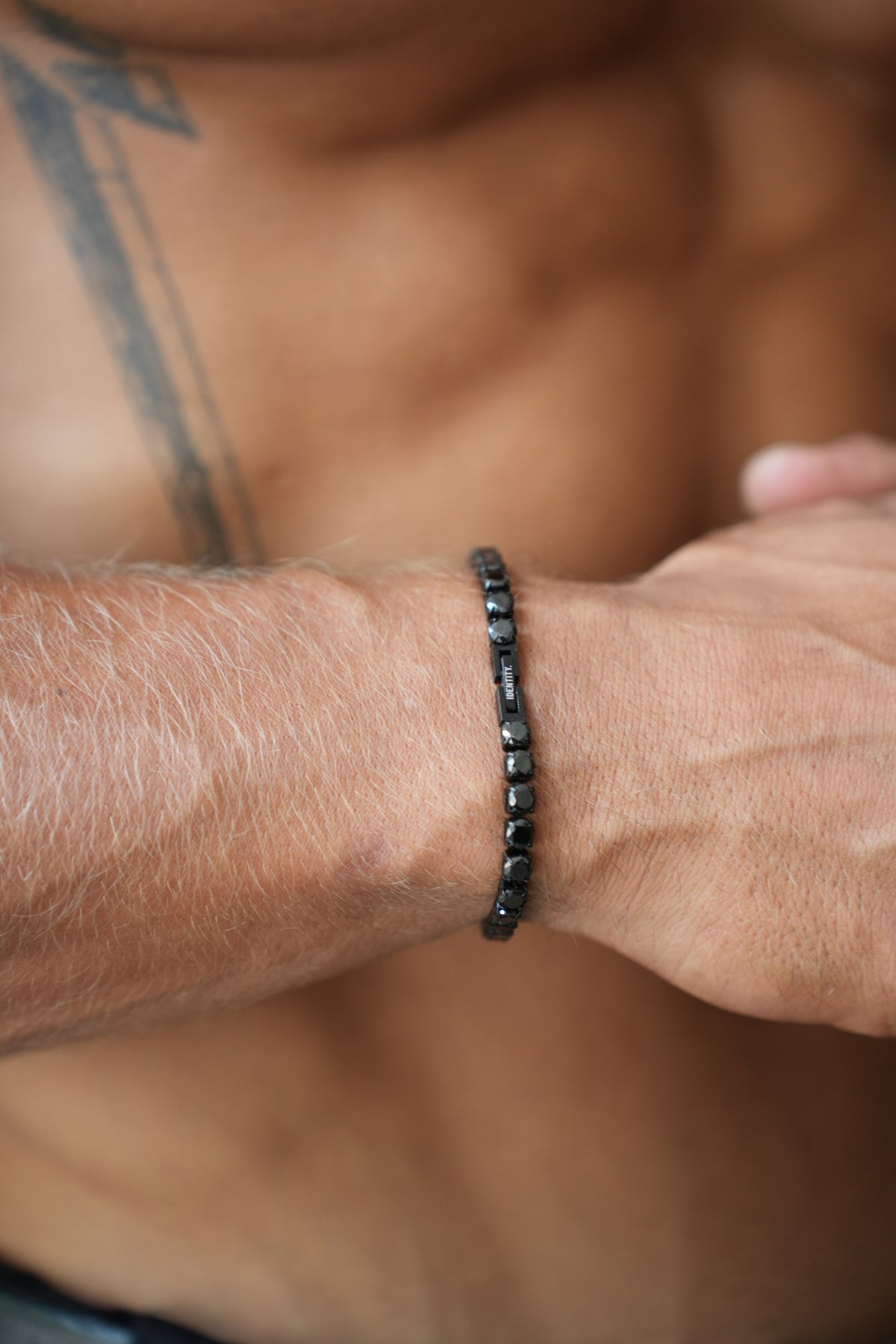 Origin Black Tennis Bracelet on the wrist with the IDENTITY. plate visible